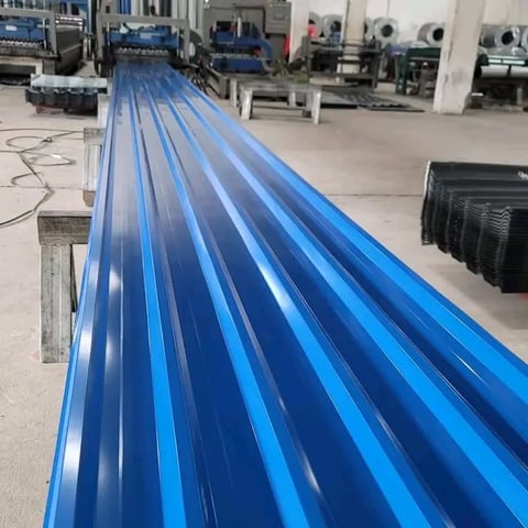 Long blue corrugated metal roofing panels lined up in an industrial warehouse facility