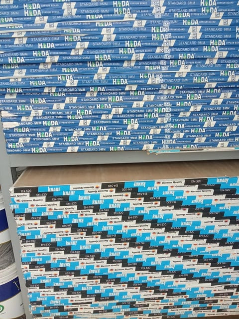 Stacked boxes of building materials with blue and white HaDA and KNAUF Knauf branded packaging labels