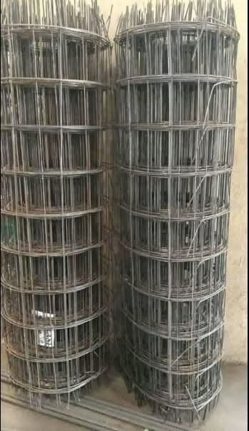 Two rolls of welded wire fencing mesh stacked vertically on a concrete surface
