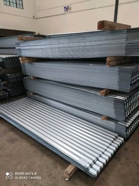 Stacked corrugated metal sheets with wooden separators in an industrial warehouse setting